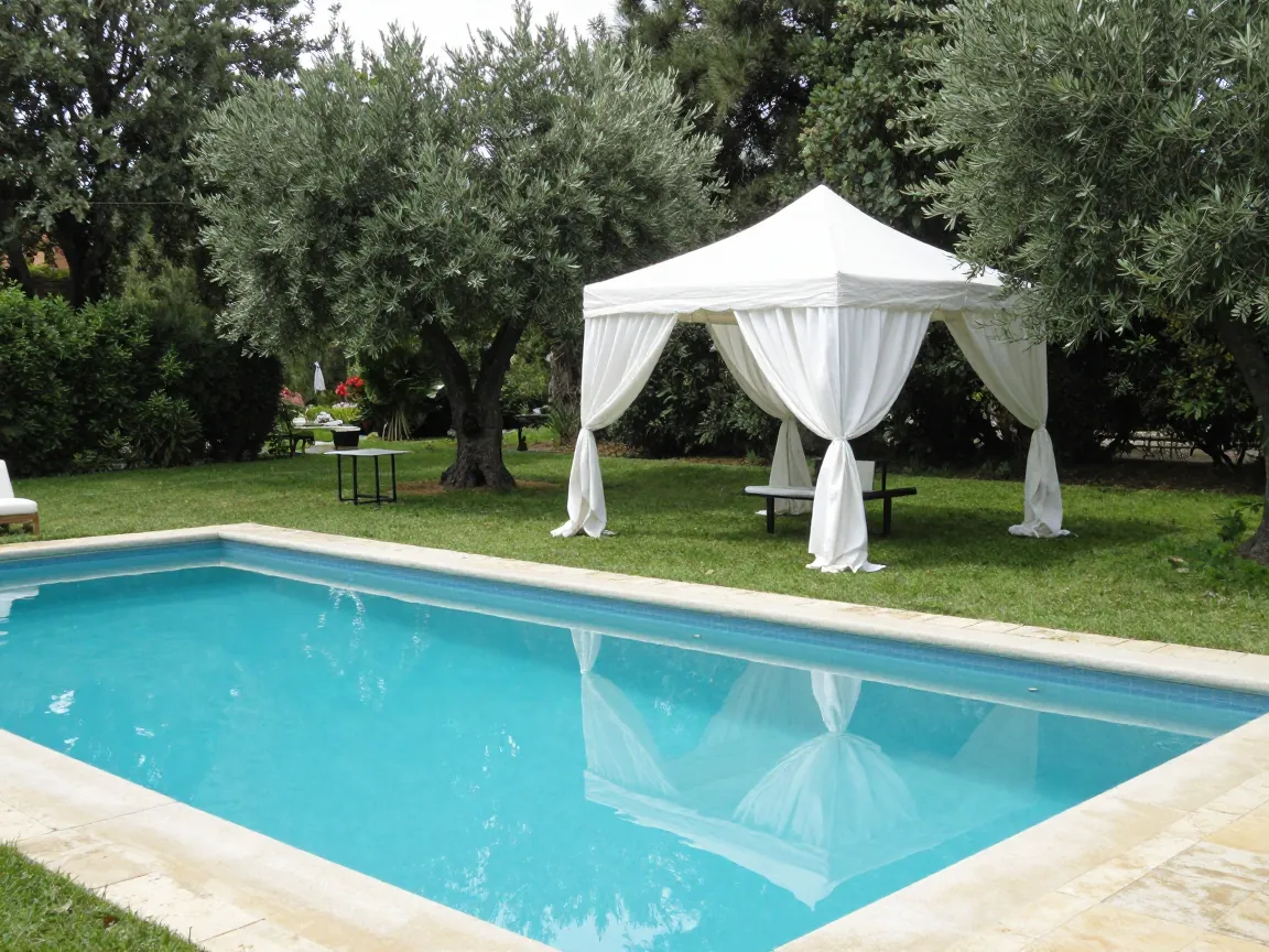 Outdoor pool at a country estate with a white canopy tent and olive trees, set up for a baptism celebration.