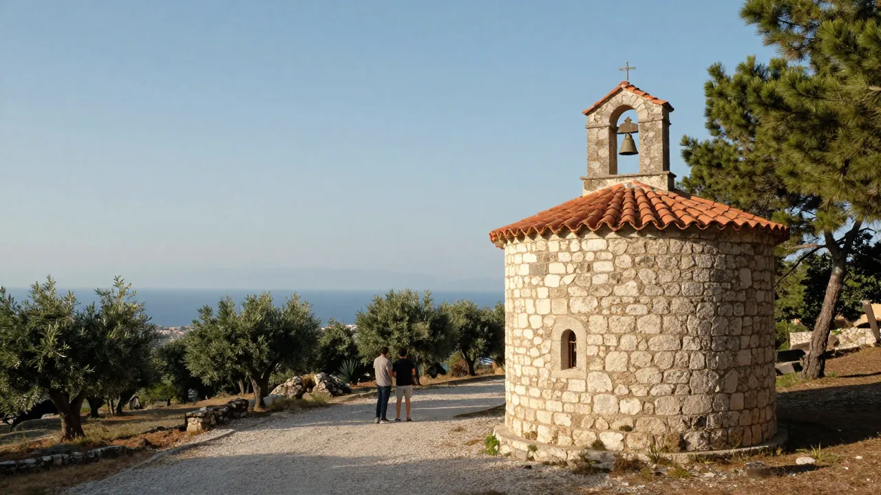 Stone chapel with tiled roof on a pine hillside in Attica, a couple seen from behind on a gravel path, olive grove and distant sea beyond.