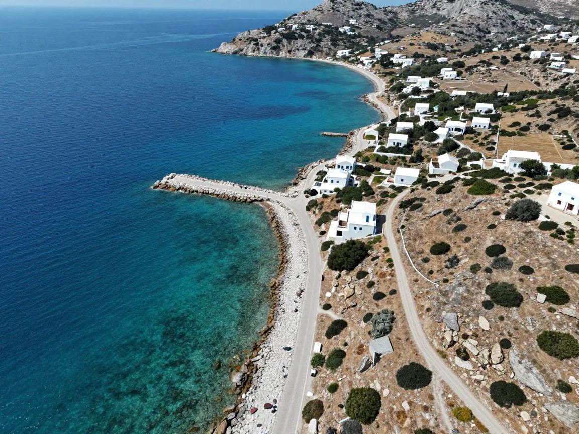 Aerial view of a rugged Greek coastline with turquoise water, a stone jetty and scattered white houses on a slope under midday sun.