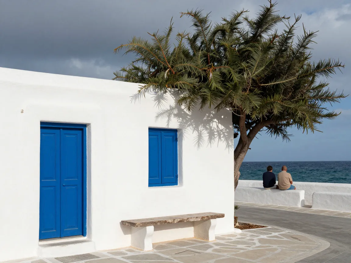 A couple waits outside a small whitewashed island airport under cloudy skies, seen from behind.